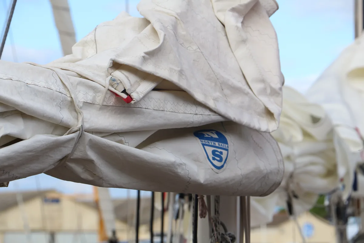Grand-voile ferlée sur la bôme d'un voilier classique, le logo North Sails sur la toile.