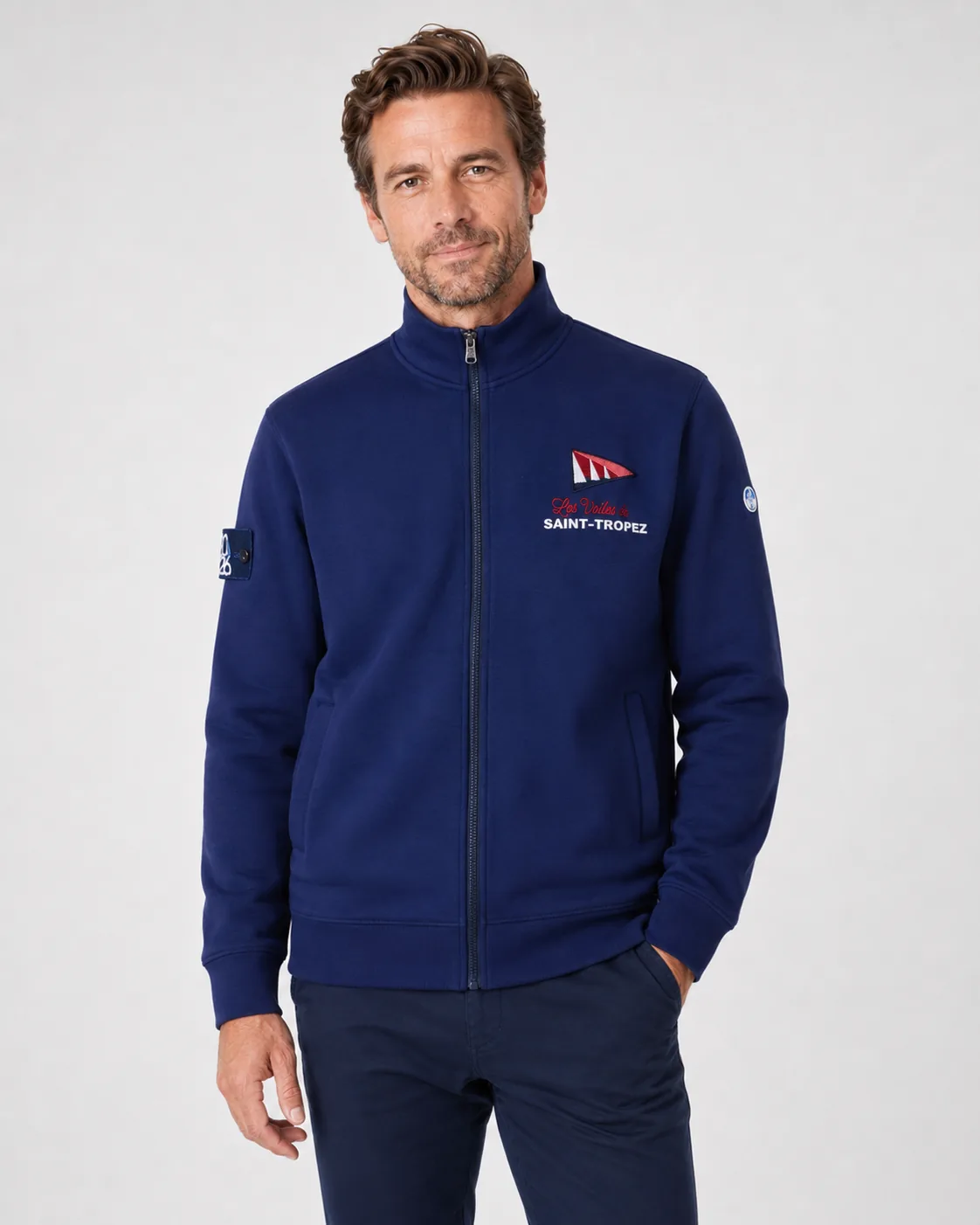 Full Zip 26 bleu marine porté de face : col montant, fermeture zippée intégrale, poches latérales et broderie du fanion Les Voiles de Saint-Tropez sur la poitrine.