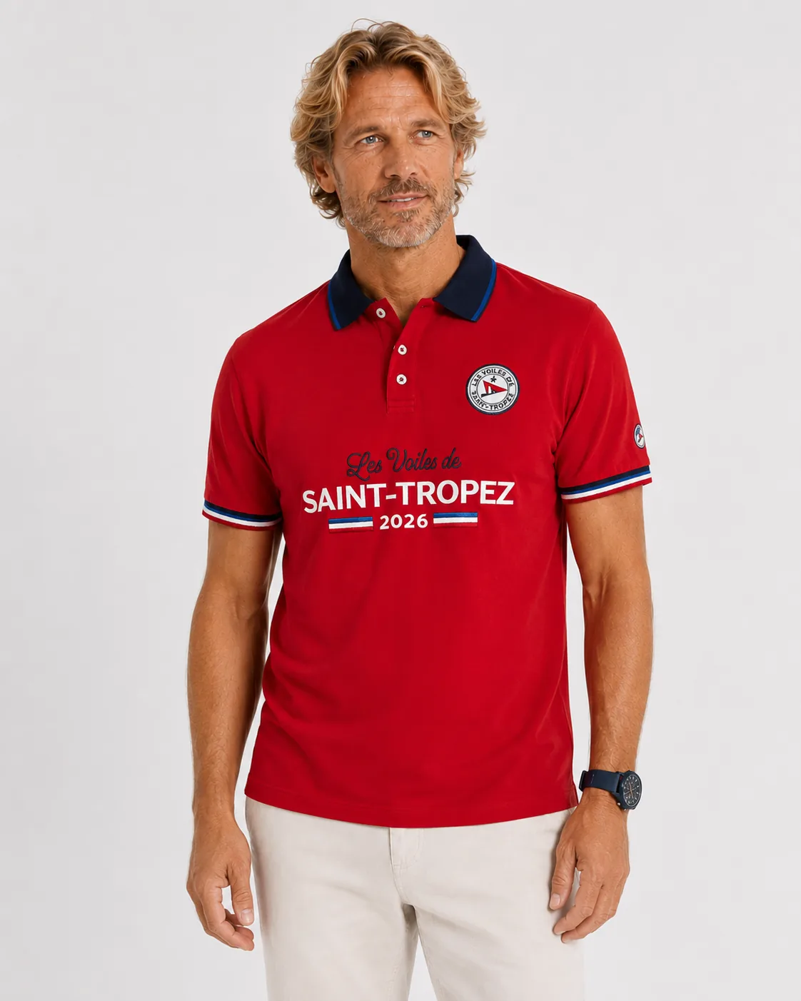 Polo Limited Edition 26 rose bougainvillier porté de face : col marine, écusson rond, mention Les Voiles de Saint-Tropez 2026 brodée en grand sur la poitrine et galons tricolores aux poignets.